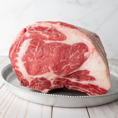 A raw, premium USDA Prime Black Angus prime rib roast showing rich intramuscular marbling and a clean fat cap, custom processed at Whole Cow.
